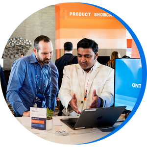 Photo of an Ontic team member demonstrating the platform to an attendee at the Product Showcase, with a branded booth setup and laptop screen displaying the Ontic interface.